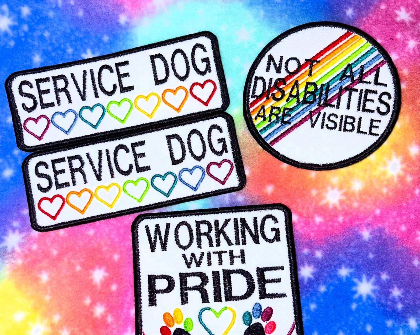 Embroidered patches on rainbow fabric: Service Dog with rainbow hearts, Working with Pride, and Not all disabilities are visible.