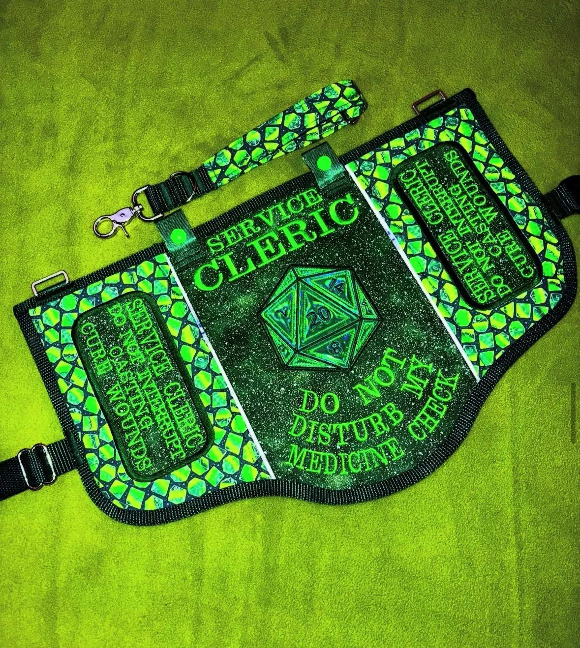 Green dragon-scale service vest with a holographic D20 and the words Service Cleric, do not disturb my medicine check, with a matching leash.