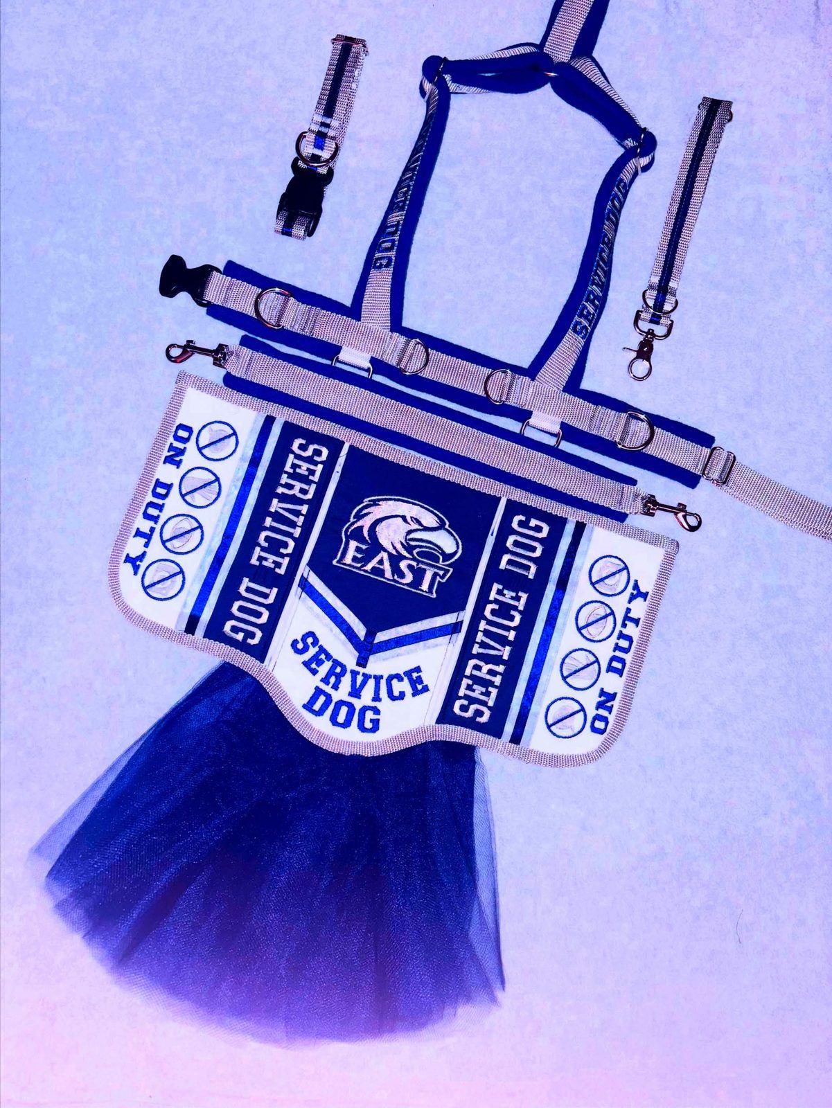Lilac and navy harness set with a vest reading Service Dog, on duty, around an eagle emblem, with a navy tulle skirt.