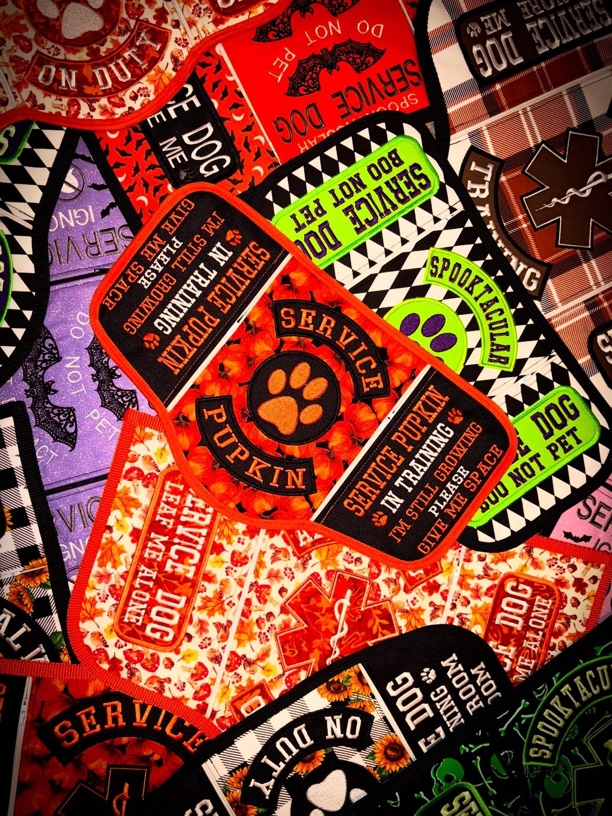 Pile of autumn and Halloween service vests reading Service Pupkin, Spooktacular and Boo not pet.